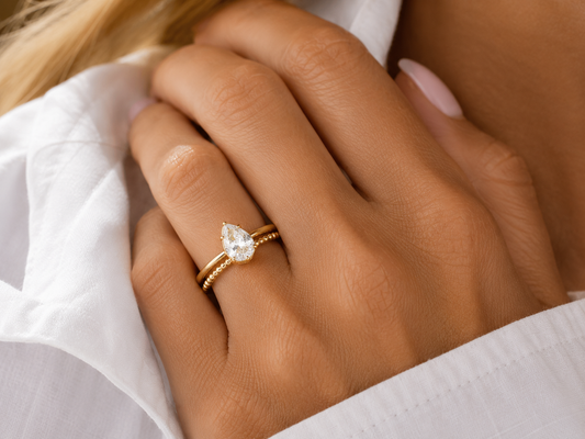 Woman wearing the Lux gold-tone pear-cut bezel ring with a clear center stone