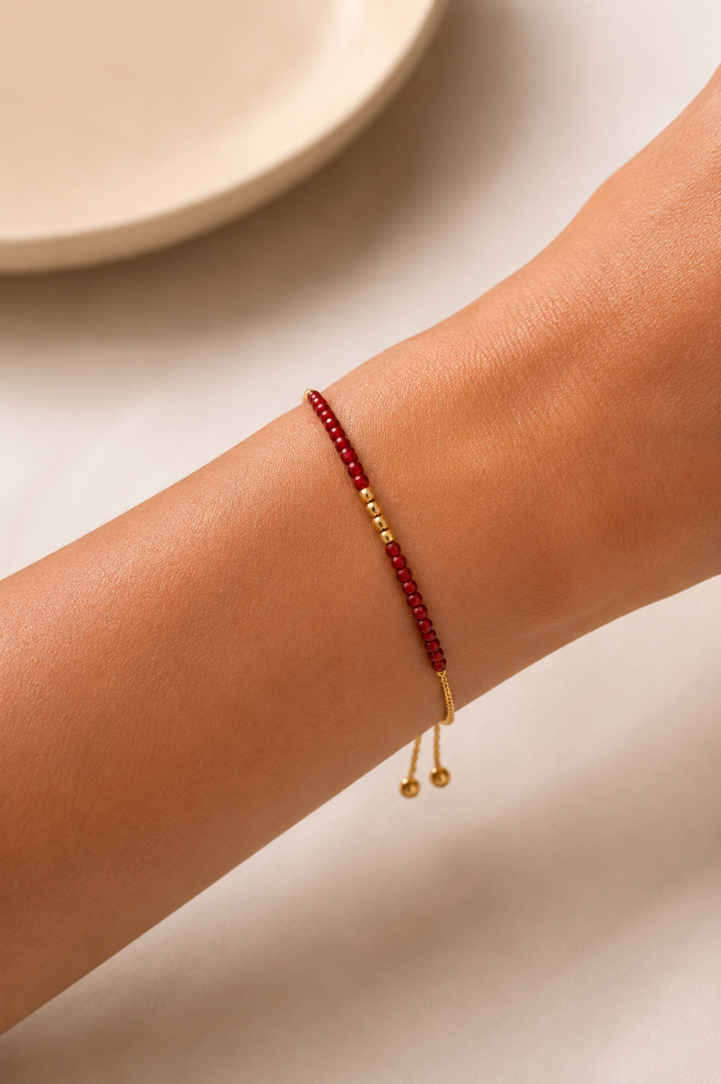 Drew red gemstone stacking bracelet with gold-tone accents worn on the wrist