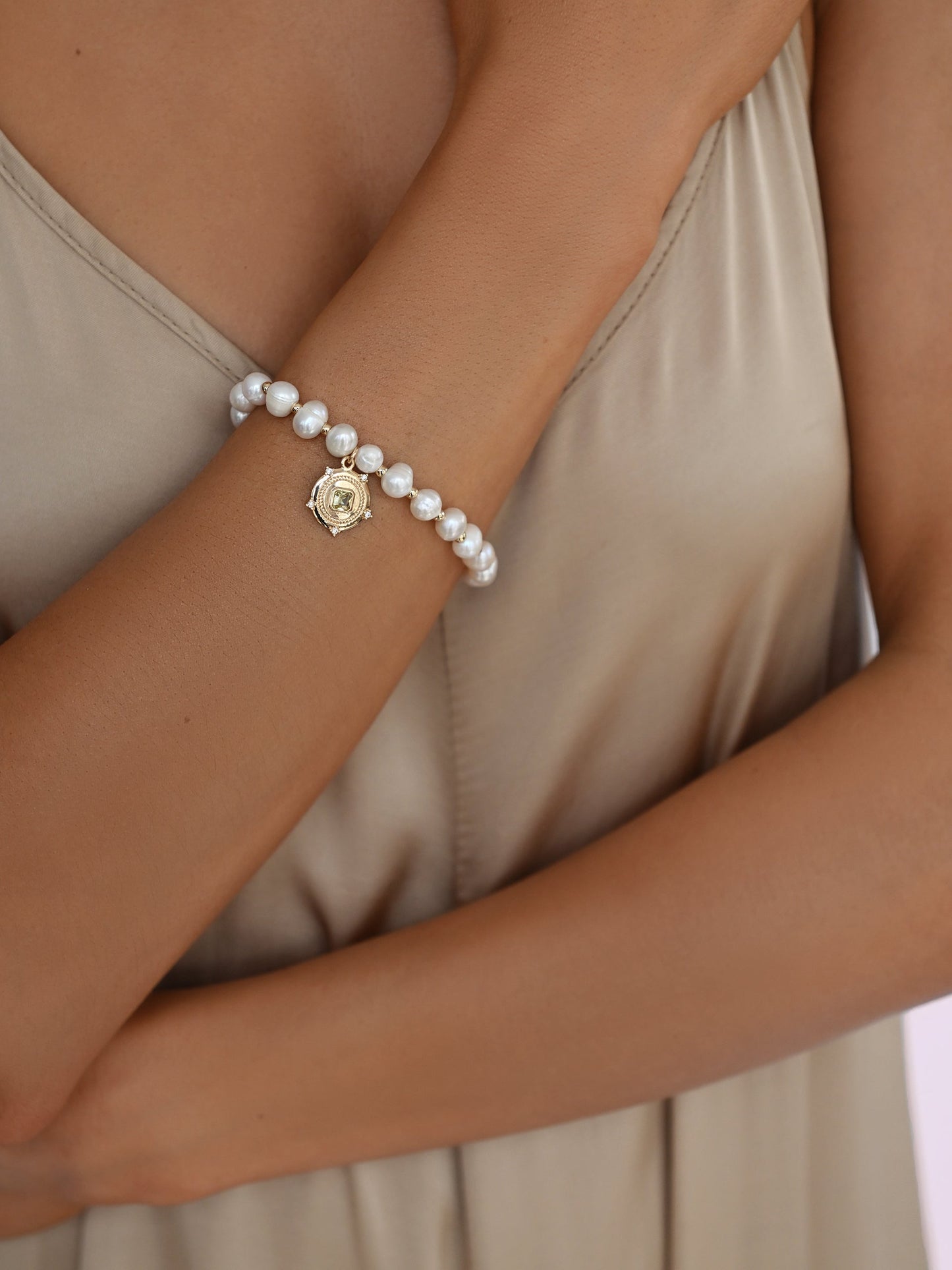 Penelope freshwater pearl bracelet worn on wrist with champagne satin top