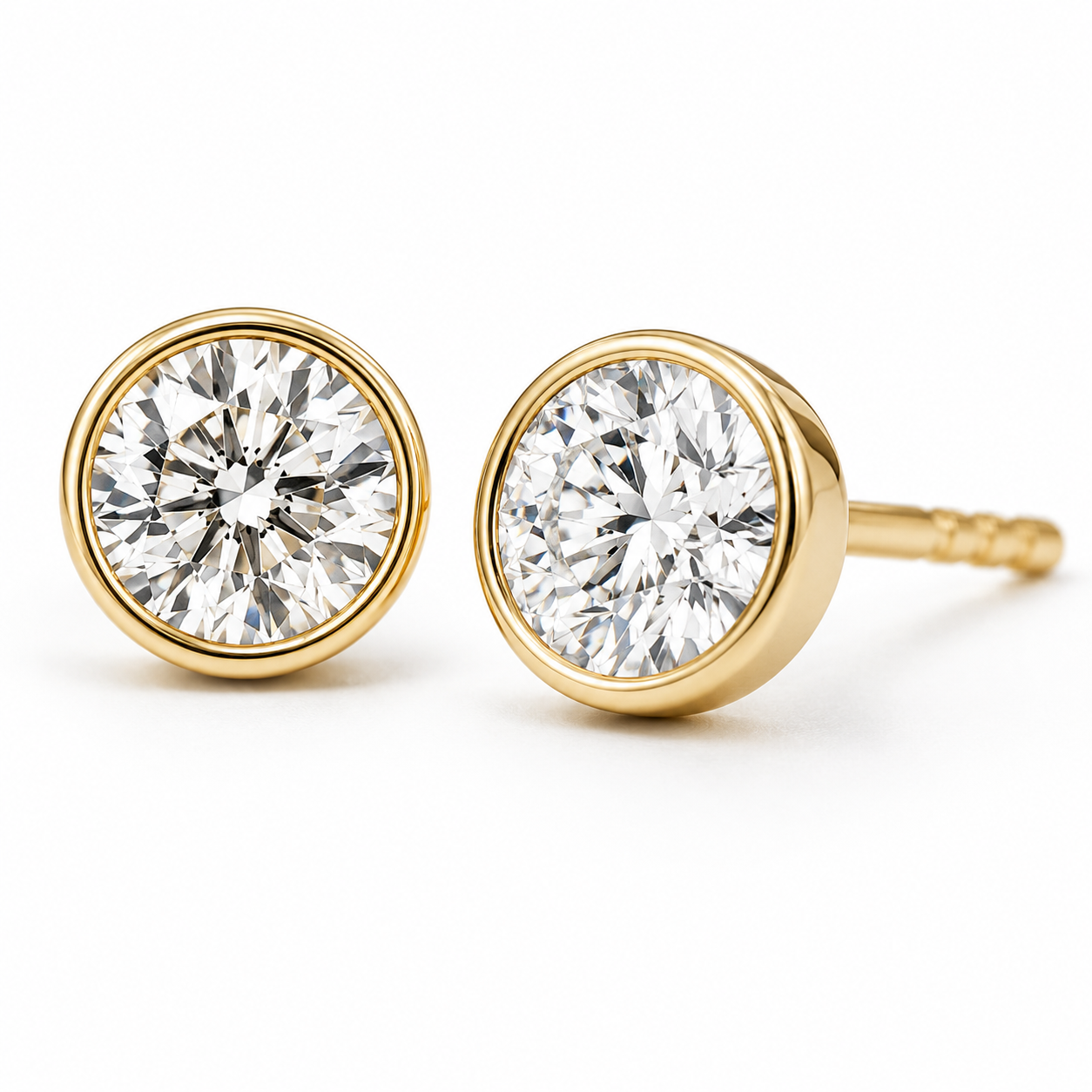 Gold bezel-set stud earrings with round clear stones on a white background