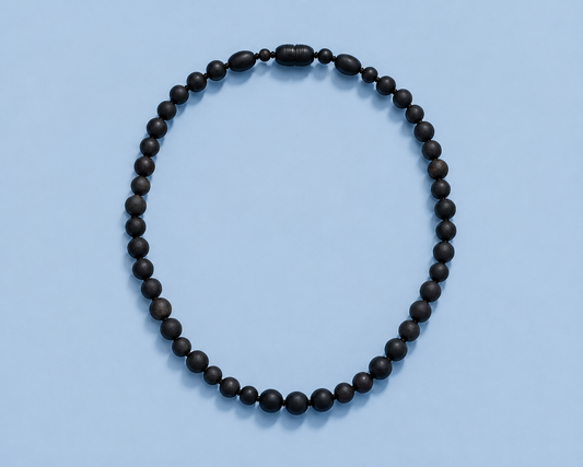 Salem black Baltic amber and shungite beaded necklace on a light blue background