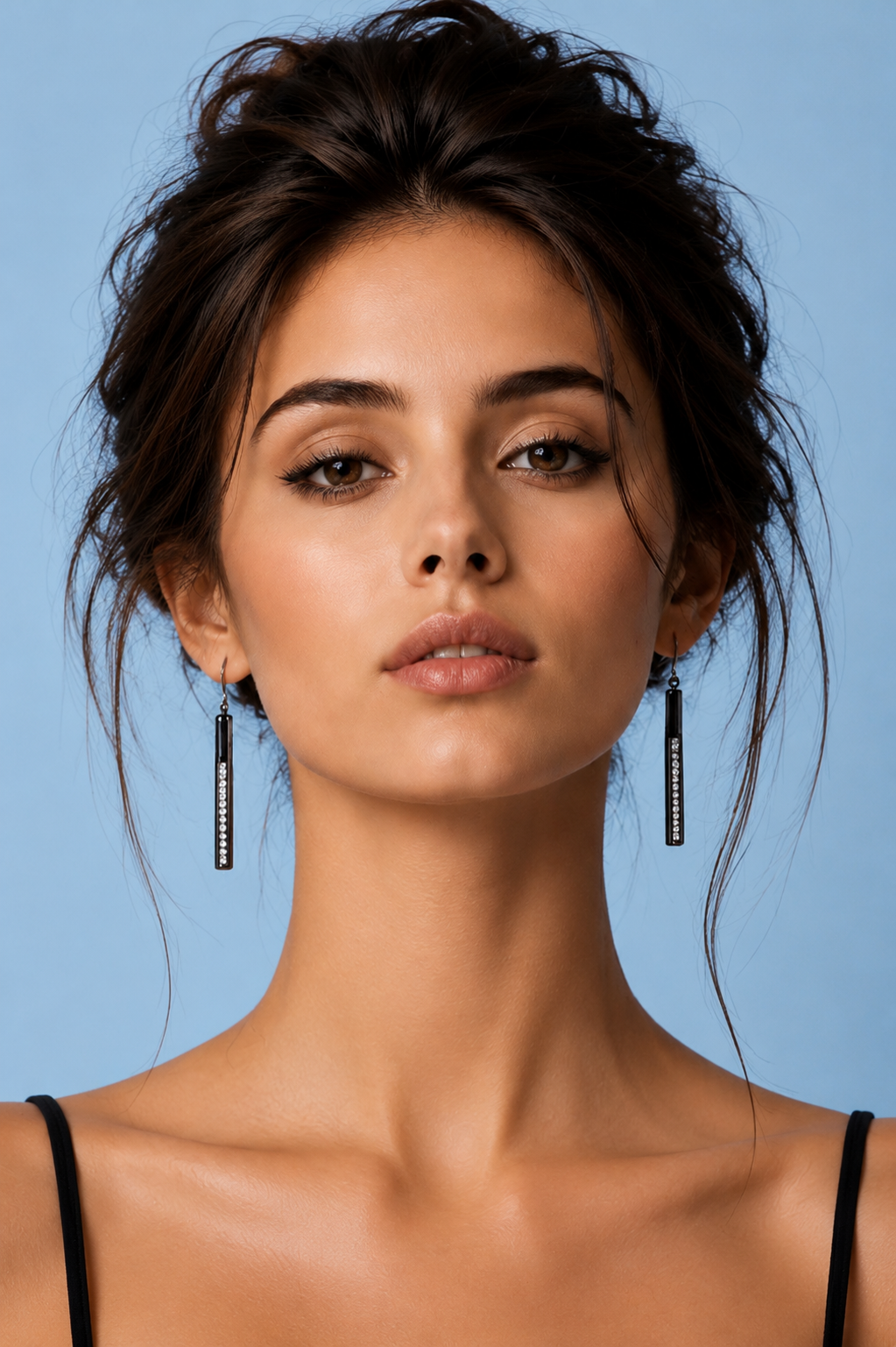     Model wearing Sloane black bar drop earrings with crystal detail on pale blue background