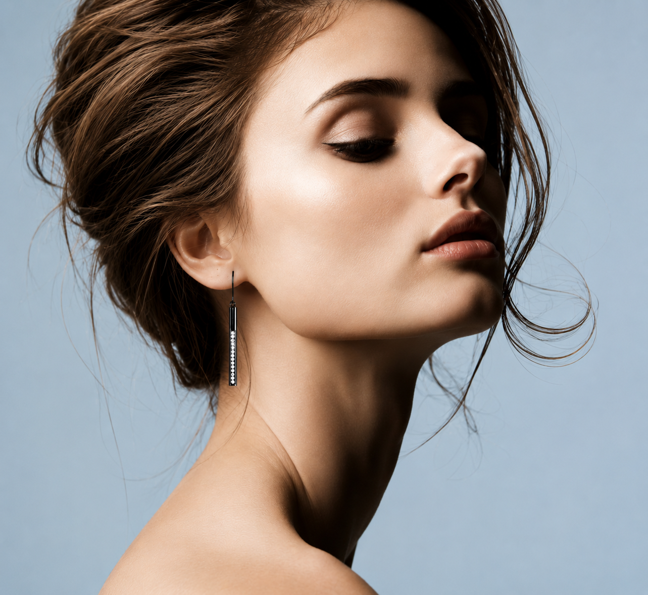     Side profile model wearing Sloane black bar drop earring on pale blue background