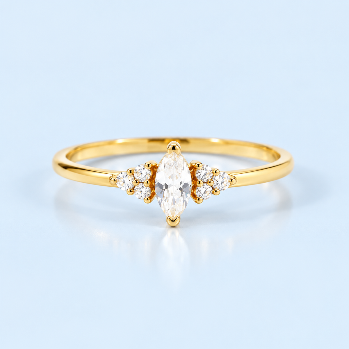 Gold Ari Marquise Ring with marquise cubic zirconia center stone on Riann Ashlyn blue background