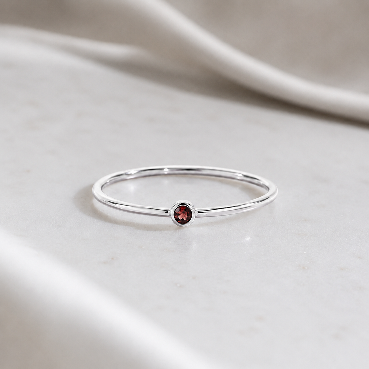     Ashlyn Tiny Garnet Birthstone Ring in sterling silver on a soft neutral background