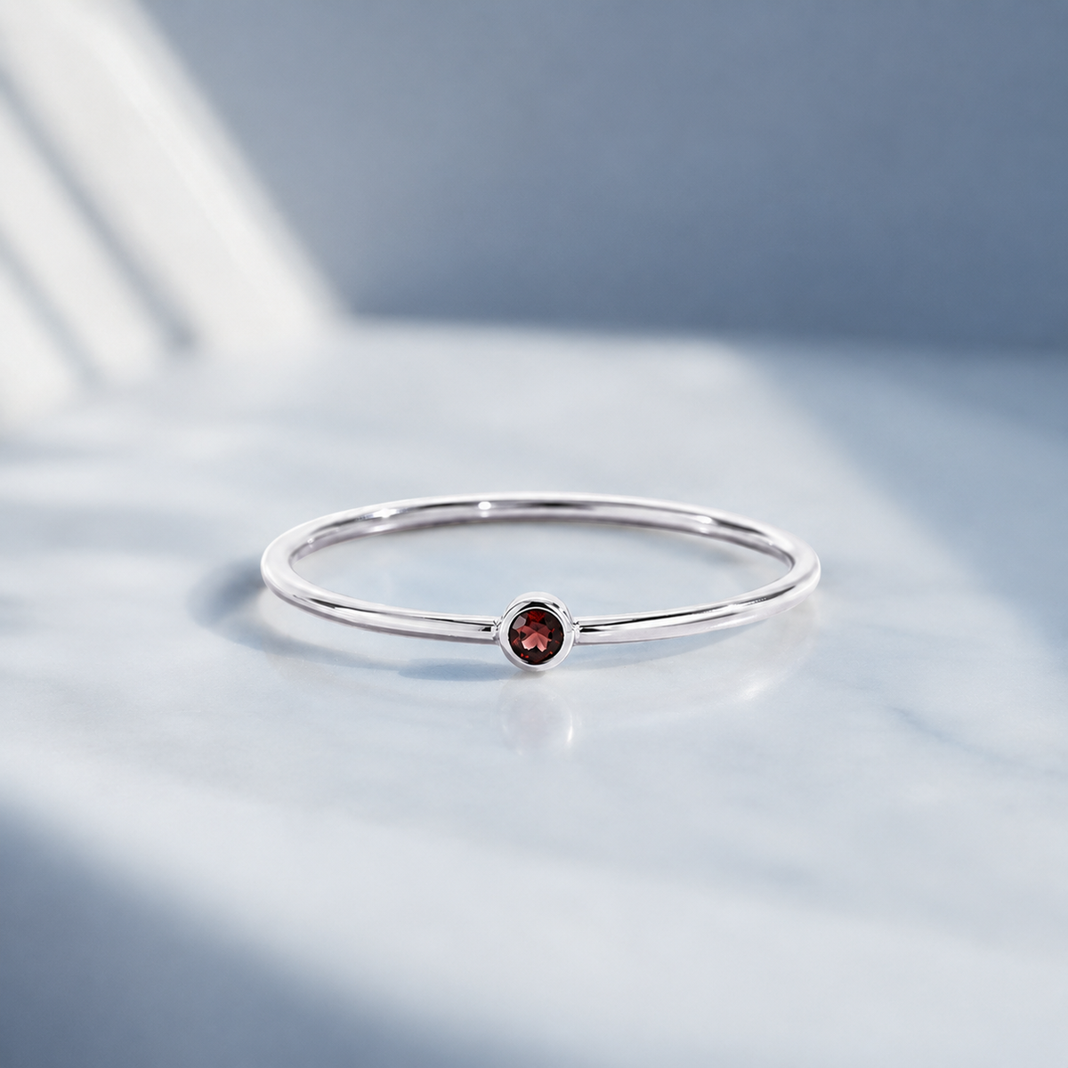     Ashlyn Tiny Garnet Birthstone Ring in sterling silver on an RA blue background