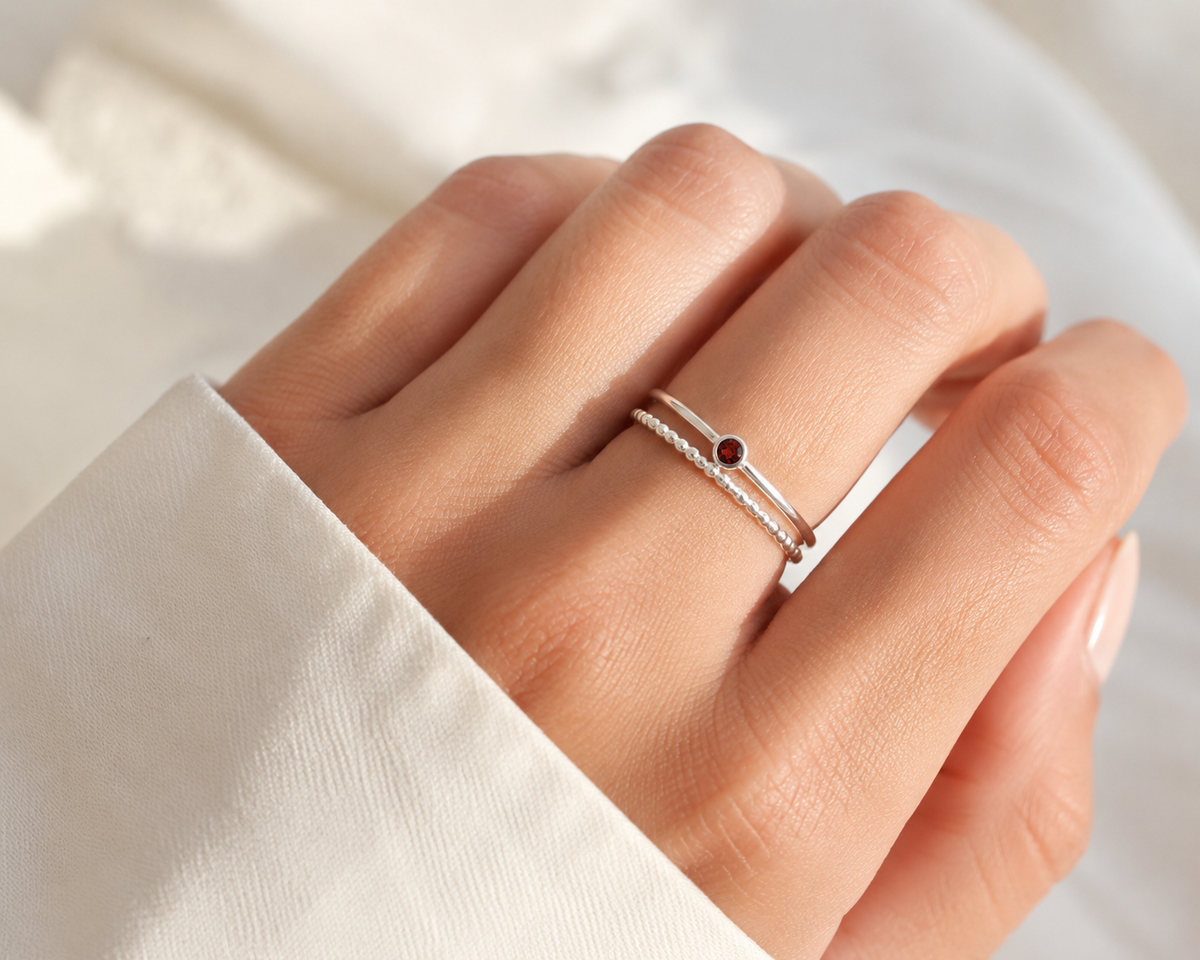     Ashlyn Tiny Garnet Birthstone Ring stacked with delicate silver rings