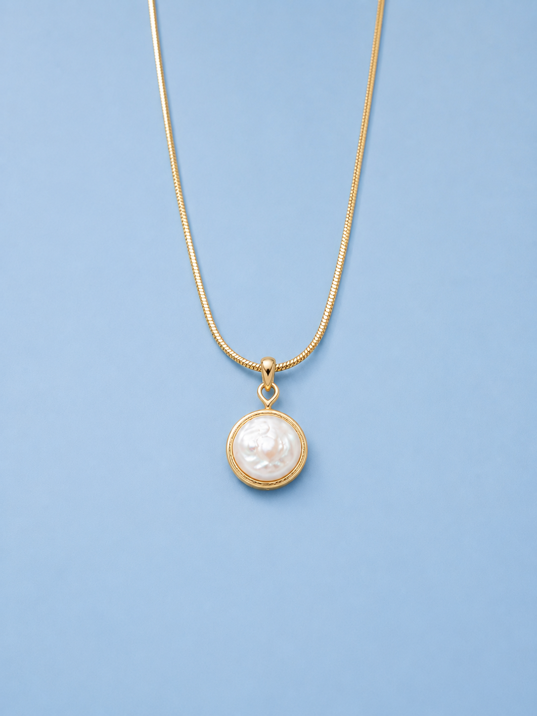 Audrey freshwater pearl pendant necklace in gold on light blue background
