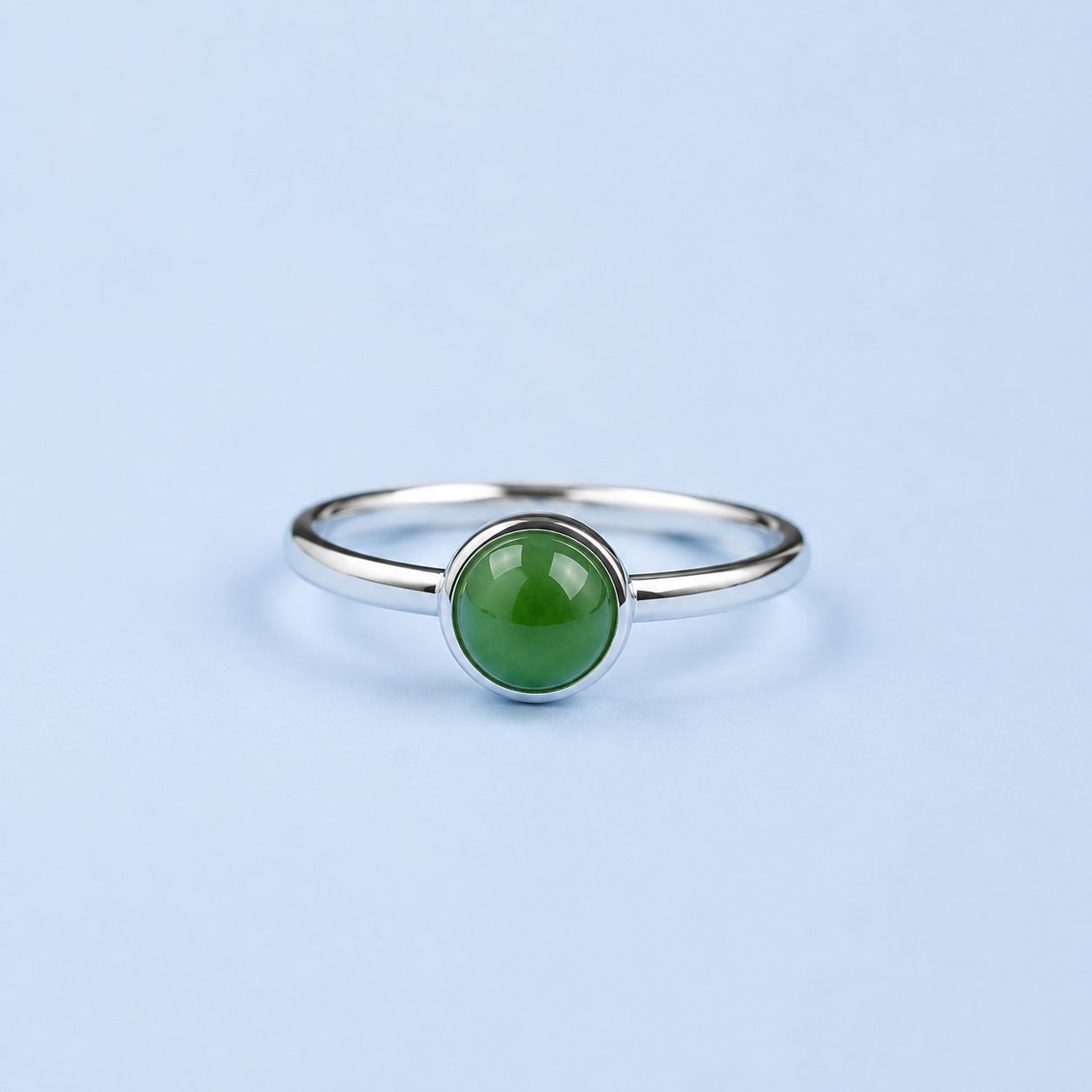     Blaise sterling silver ring with a round green nephrite jade cabochon on a light blue background.