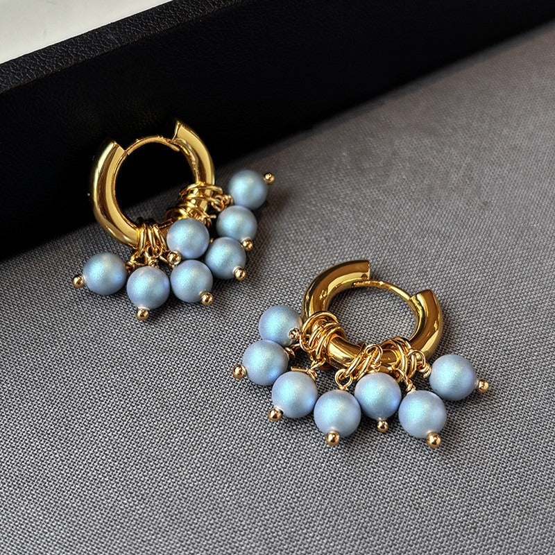 Blu Pearl gold hoop earrings with clusters of light blue pearl beads displayed on a gray background.