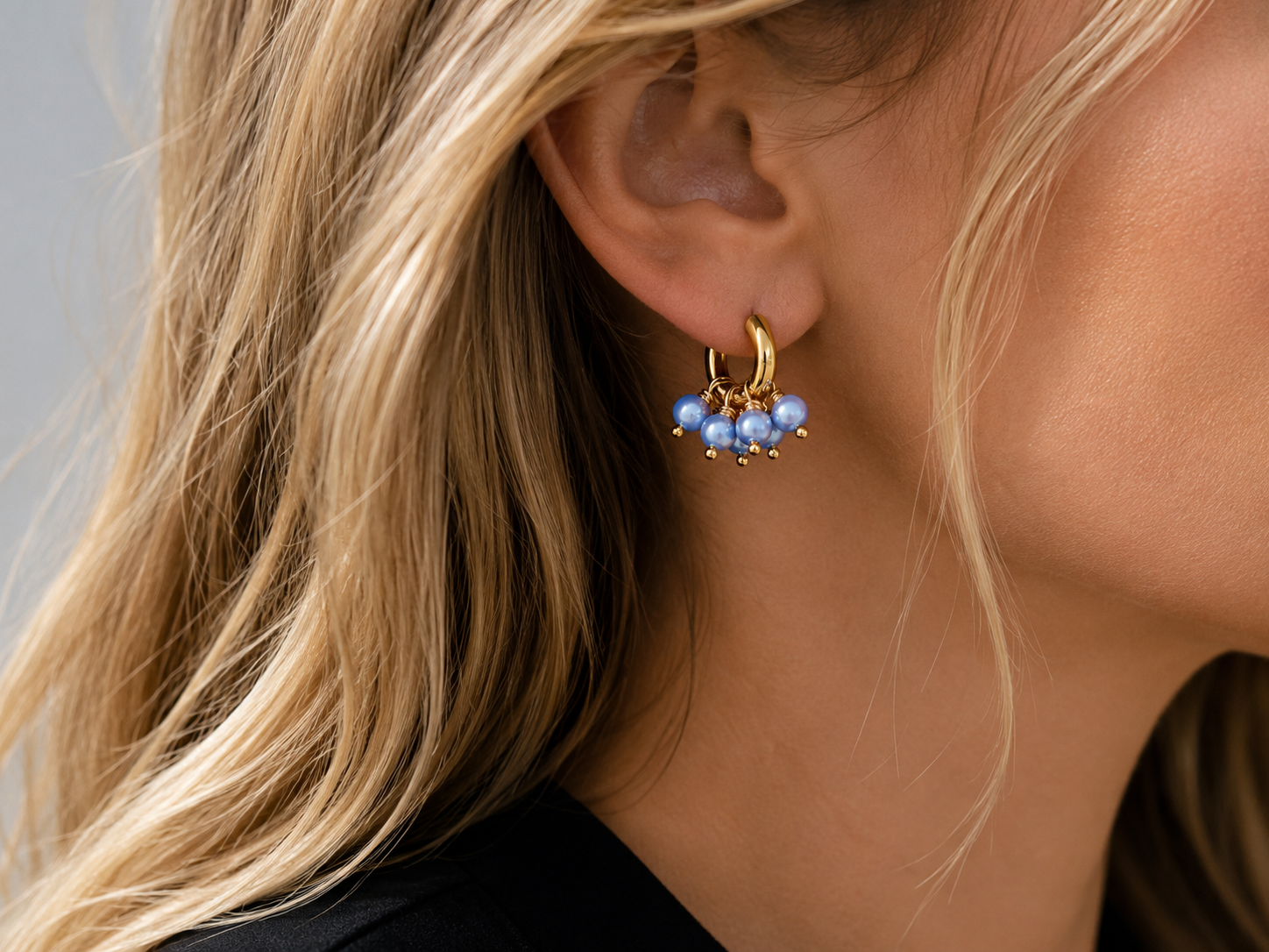 Model wearing Blu Pearl gold hoop earrings with a cluster of light blue pearl beads.