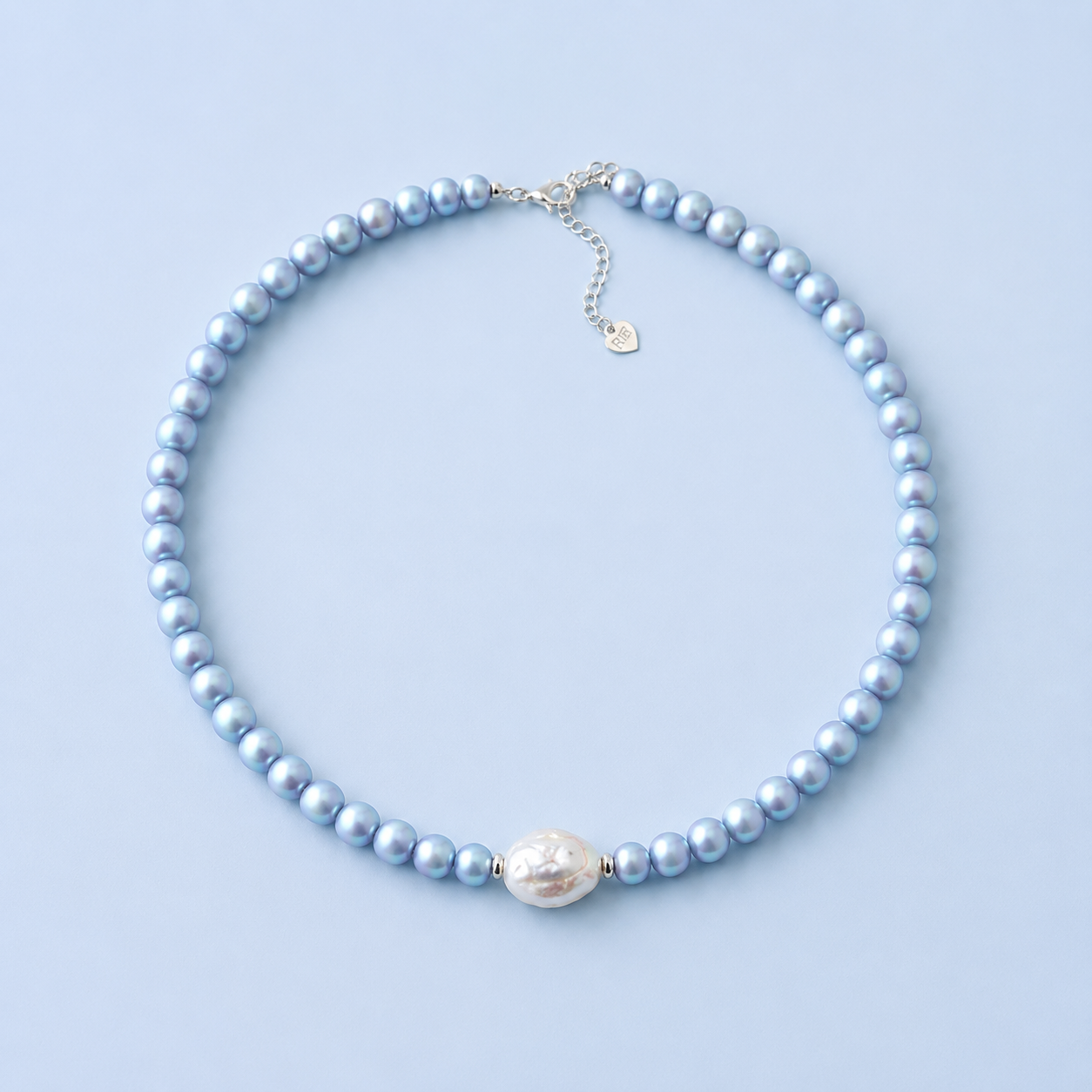 Blu Pearl Necklace with light blue pearl beads and a single irregular white freshwater pearl centerpiece on a light blue background.