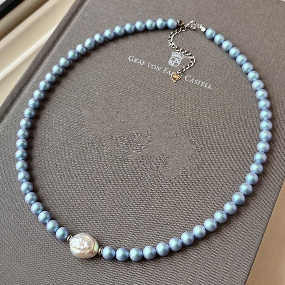 Close-up of the Blu Pearl Necklace with light blue pearl beads and a single irregular white freshwater pearl centerpiece.