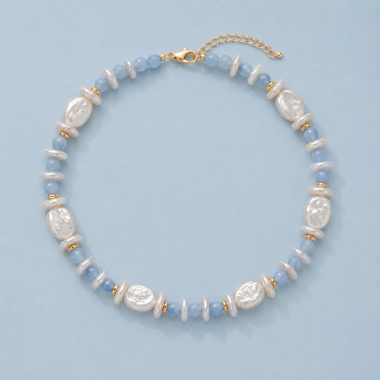 White baroque pearl and light blue beaded necklace with gold-tone spacers on a light blue background