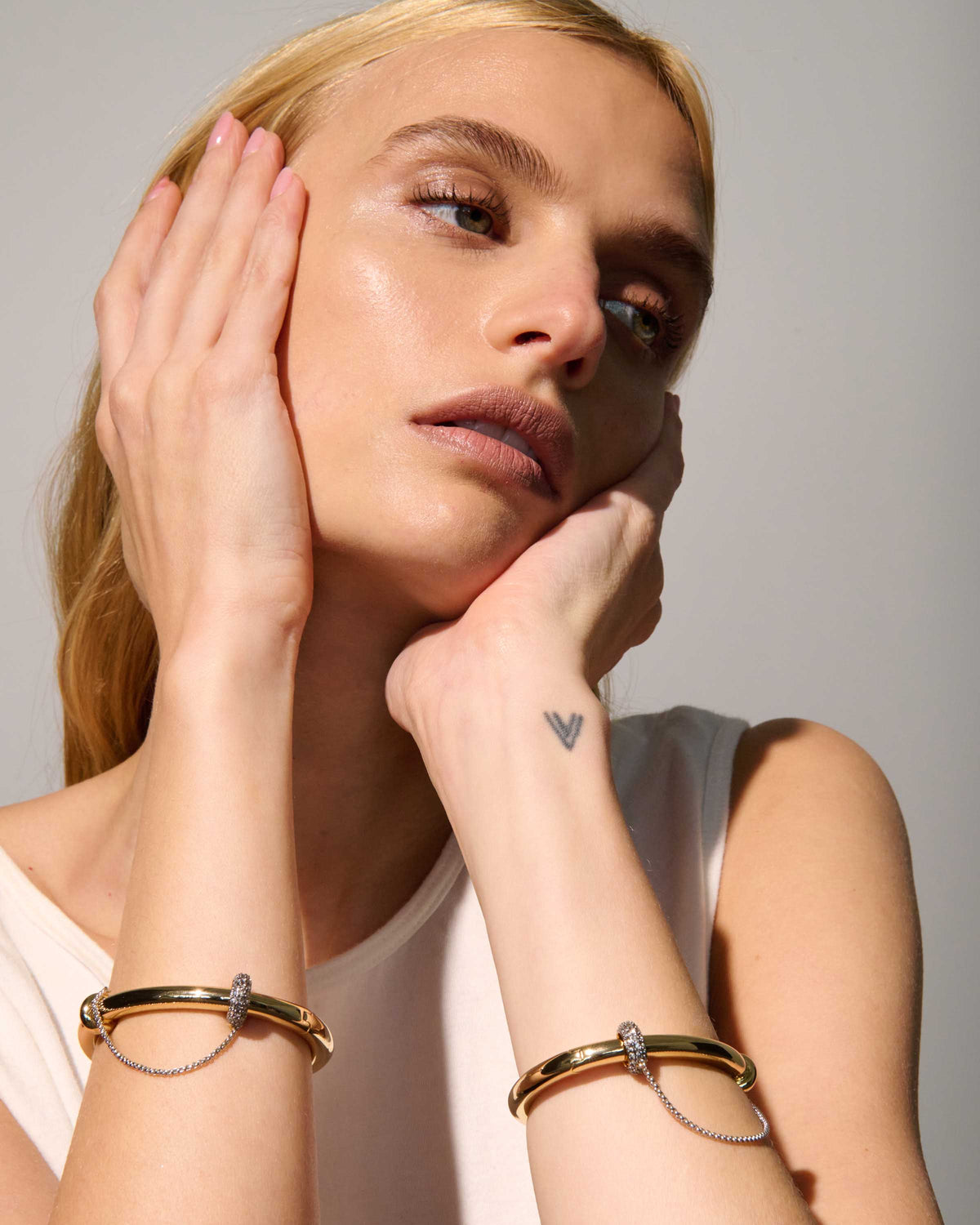 Channing Sculptural Bangle Bracelet from The Riann Ashlyn Collection, styled with coordinating bracelets on a model wearing a white sleeveless top.
