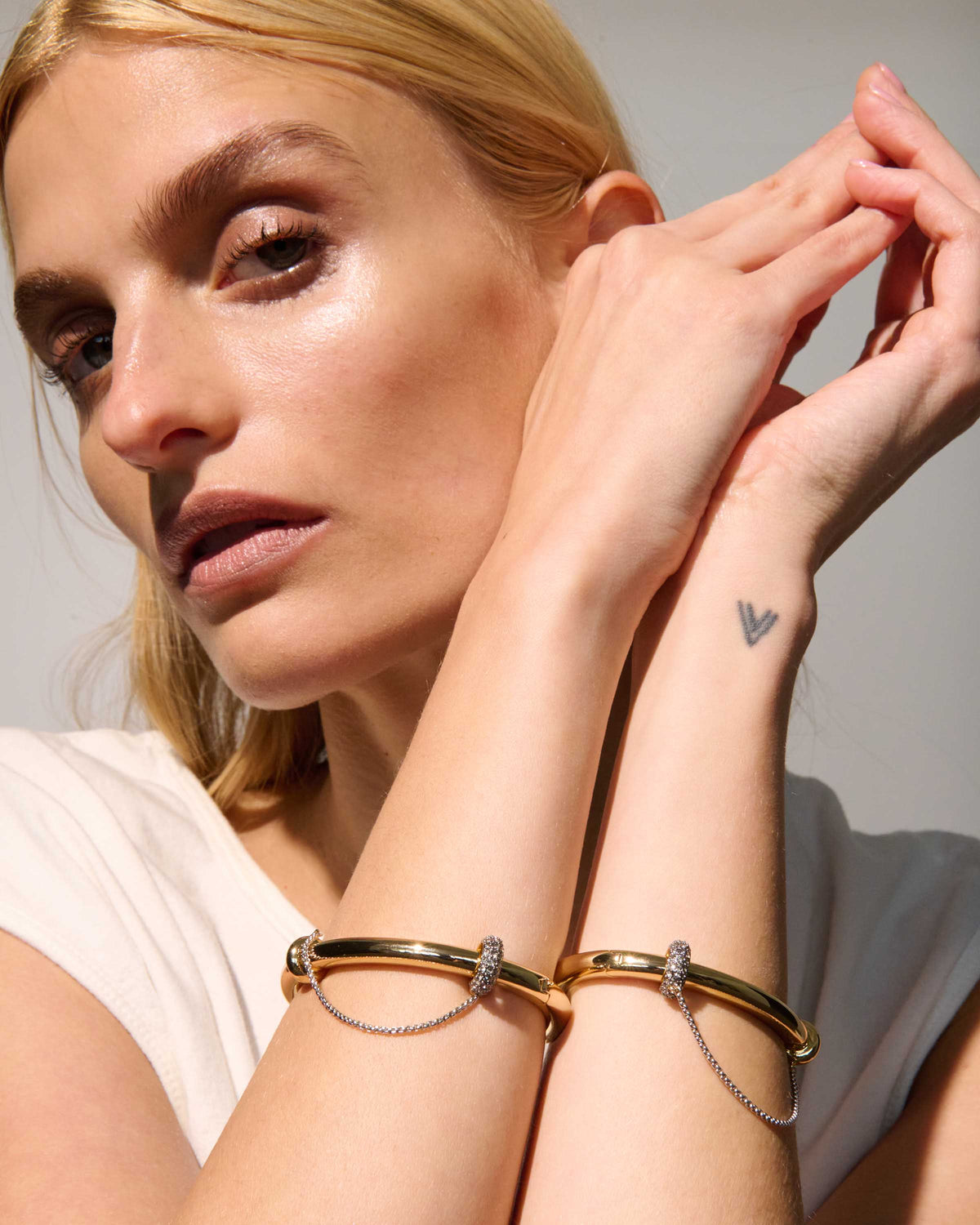 Channing Sculptural Bangle Bracelet from The Riann Ashlyn Collection, styled on a model's wrist alongside gold-tone bracelets.