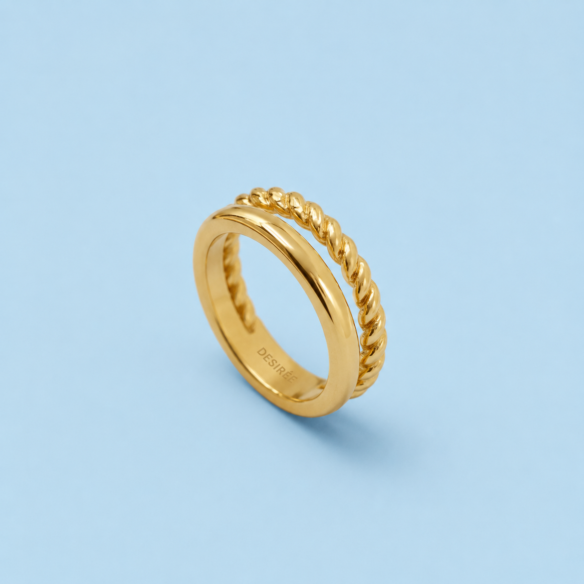 Cleo gold double band ring with smooth and twisted rope bands on pale blue background