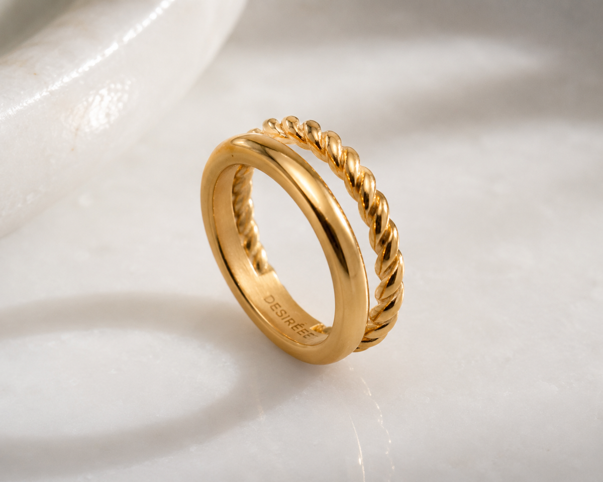 Cleo gold double band ring with smooth band and twisted rope detail on white surface