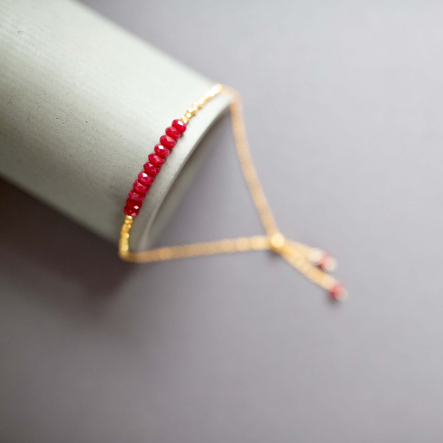 Close-up of Drew red gemstone stacking bracelet with gold-tone adjustable chain