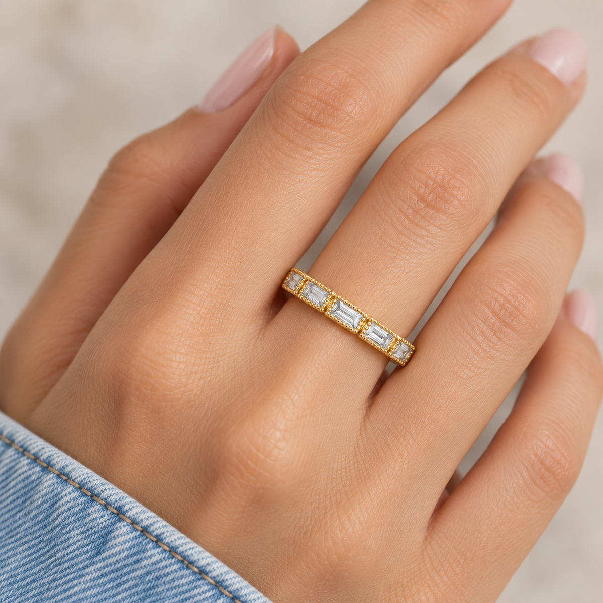 Fallon gold-plated baguette ring worn on hand with denim sleeve