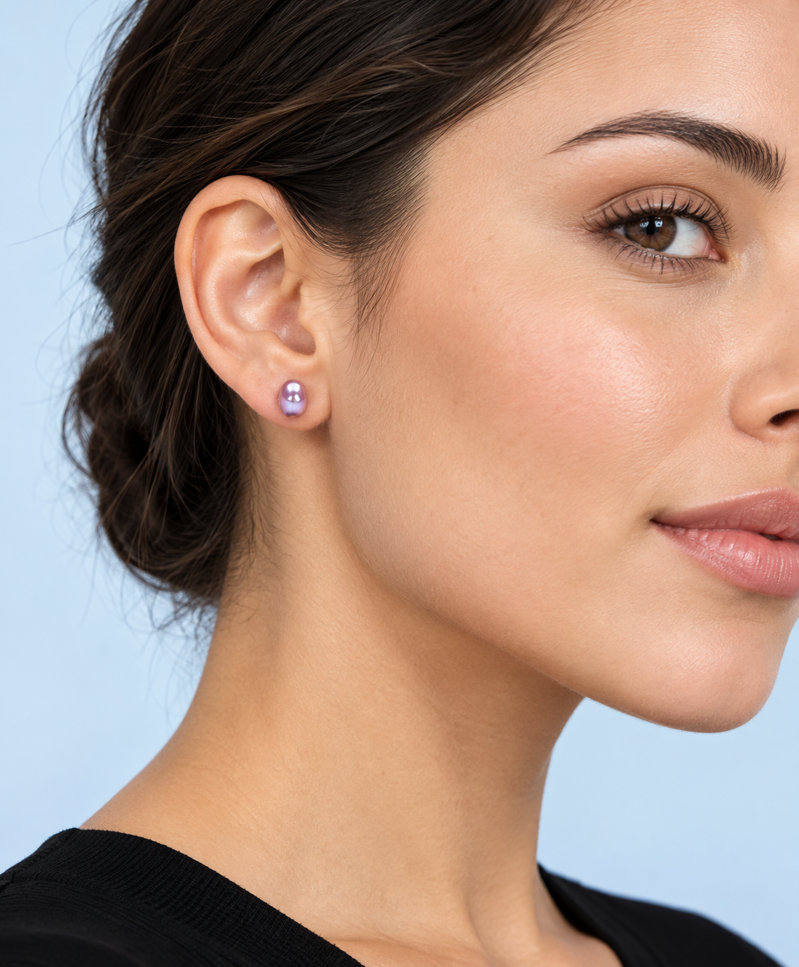 Model wearing a Hadley lavender pearl stud earring with a black top against a pale blue background