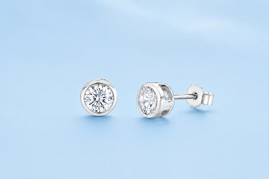 Harper sterling silver simulated diamond bezel-set stud earrings on a light blue background, shown from front and side.