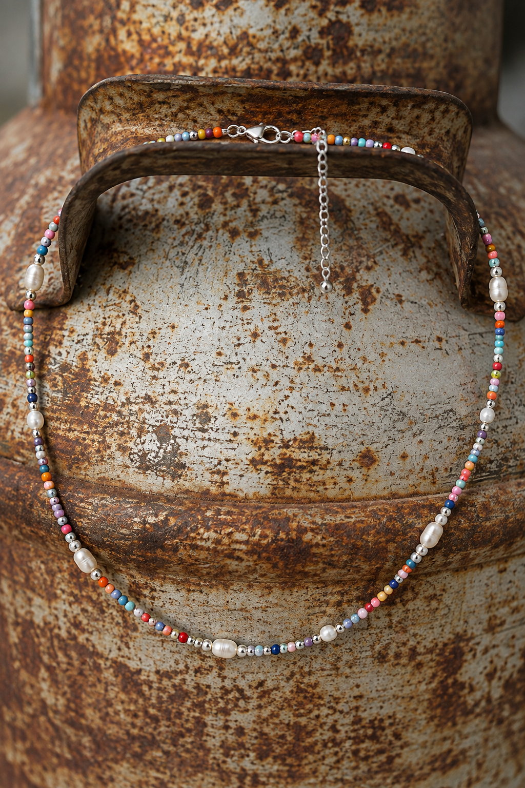 Close-up of the Indy Necklace with multicolor beads, sterling silver beads and genuine freshwater pearls on a rustic metal background.