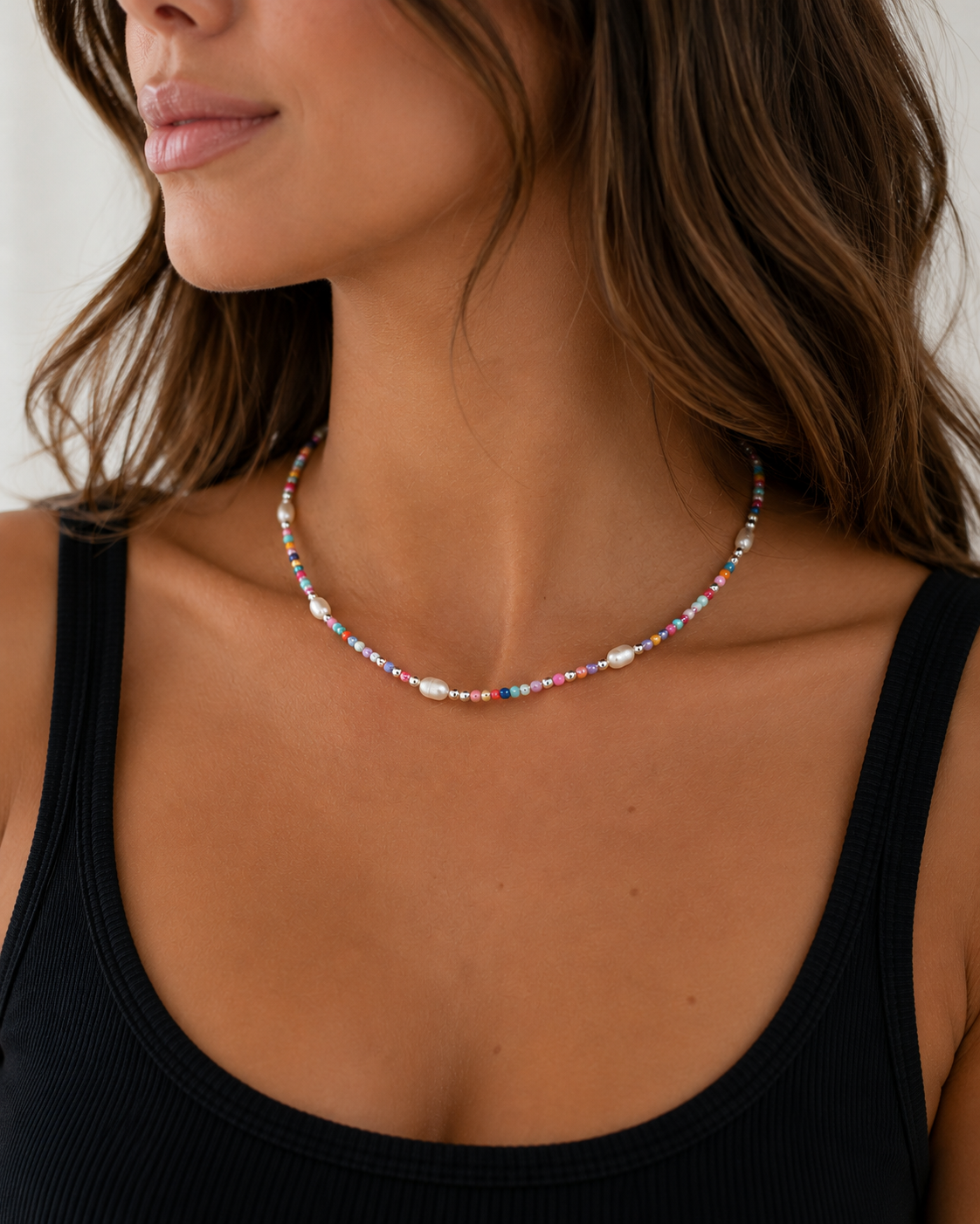 Woman wearing the Indy Necklace with multicolor beads, sterling silver beads and genuine freshwater pearls with a black tank top.