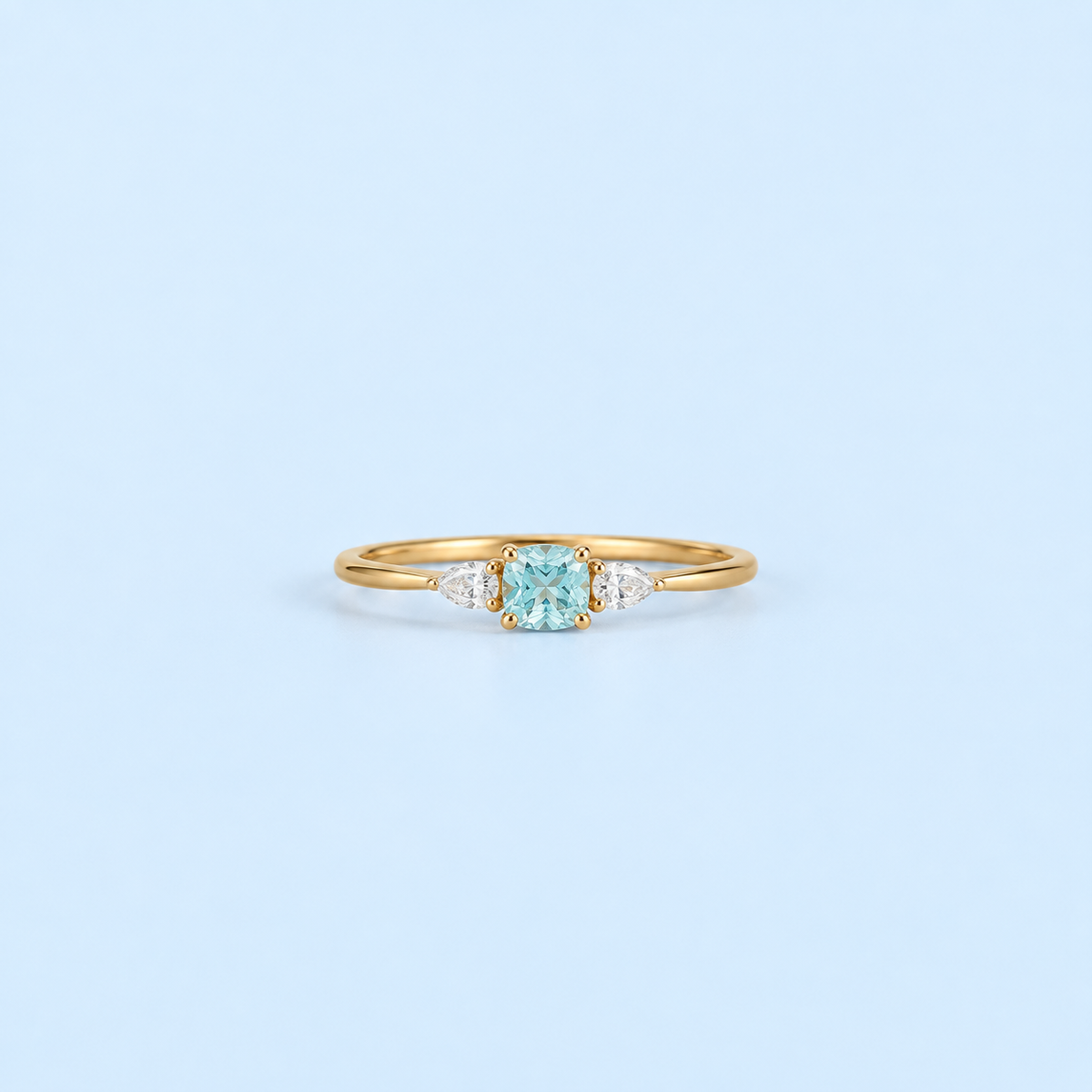 Gold Kennedy Aquamarine Blue Cushion Ring with blue cushion-cut cubic zirconia on Riann Ashlyn blue background