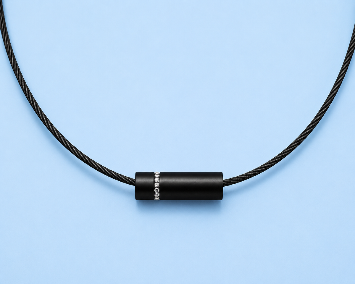     Close-up of Knox black cylindrical pavé pendant necklace on a pale blue background