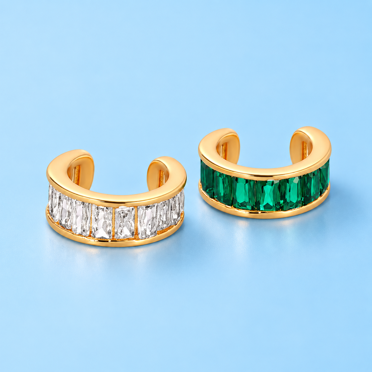     Lainey Crystal Ear Cuff in clear and emerald crystal on a light blue background