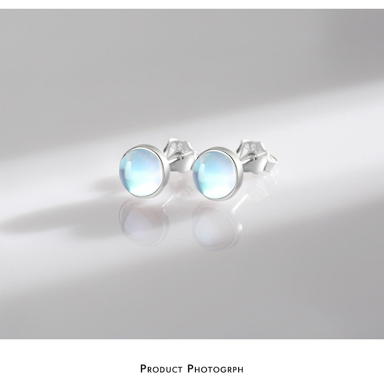 Pair of Lumi pale blue stud earrings on a light gray surface with soft shadows.
