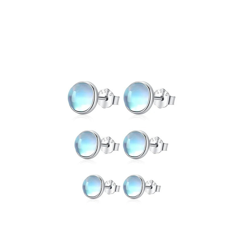 Three pairs of Lumi pale blue stud earrings arranged vertically to compare their sizes.