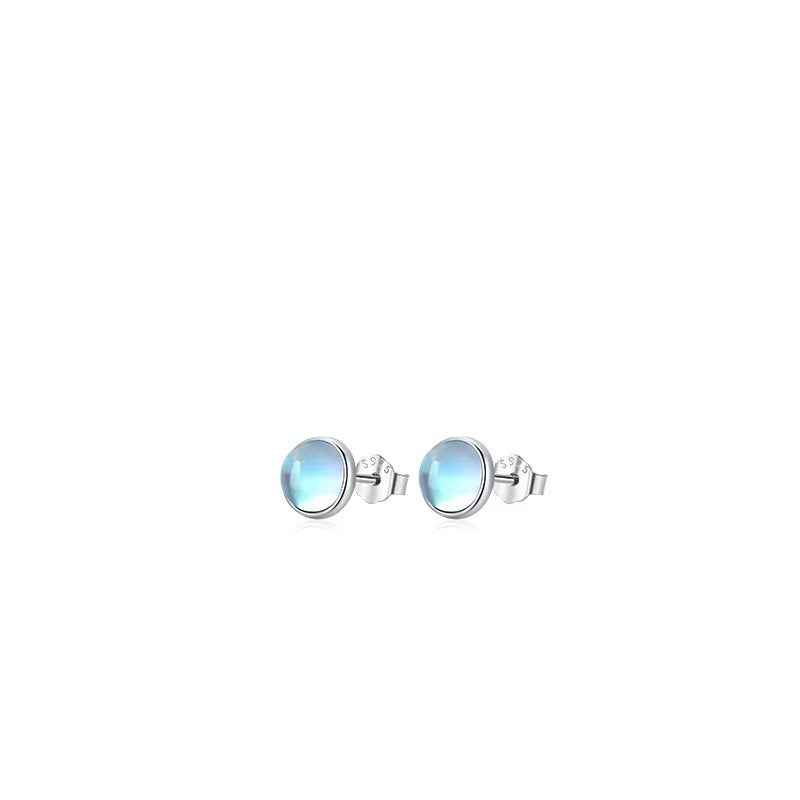 Small pair of Lumi round pale blue stud earrings with silver-tone settings on white.