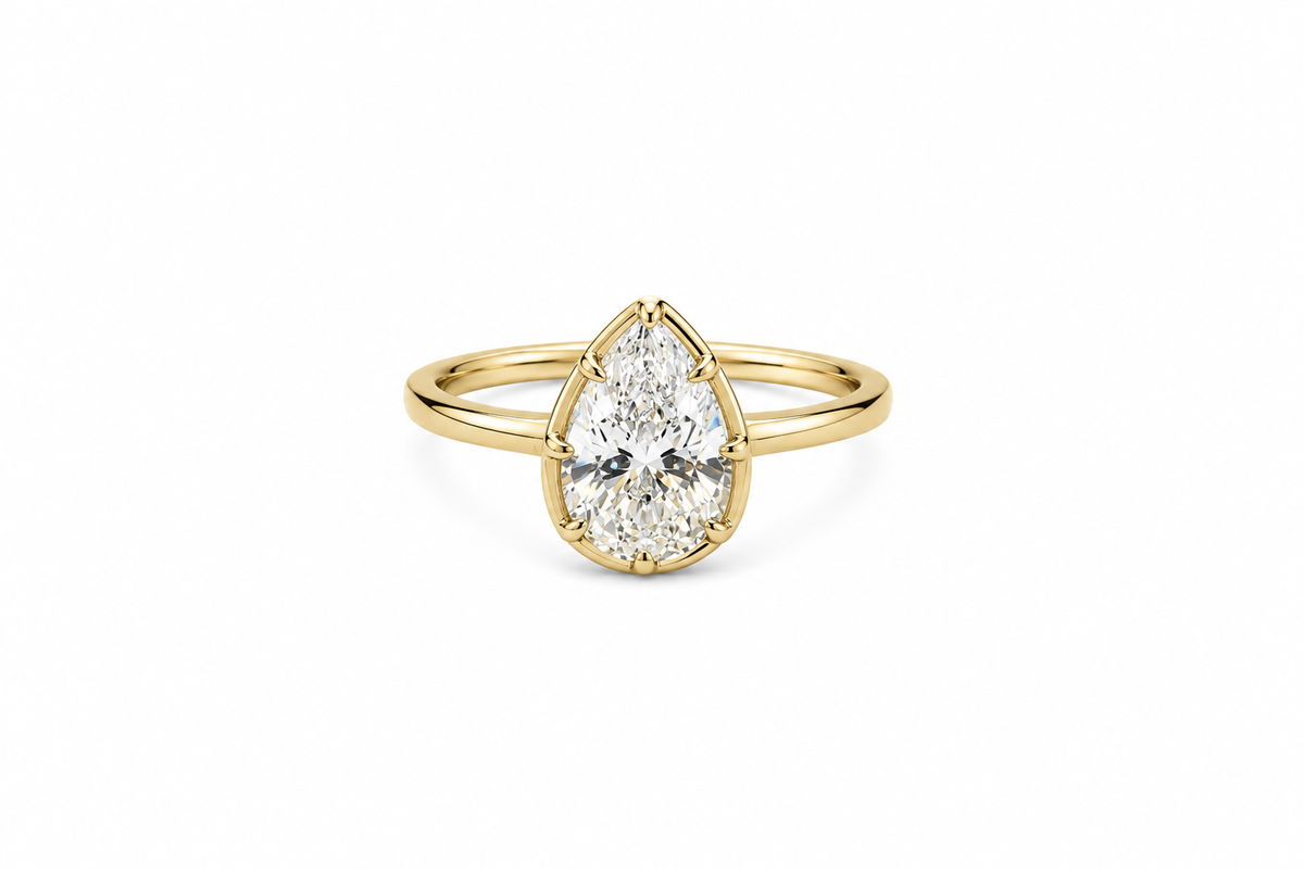 Lux gold-tone pear-cut bezel ring with a clear center stone on a white background