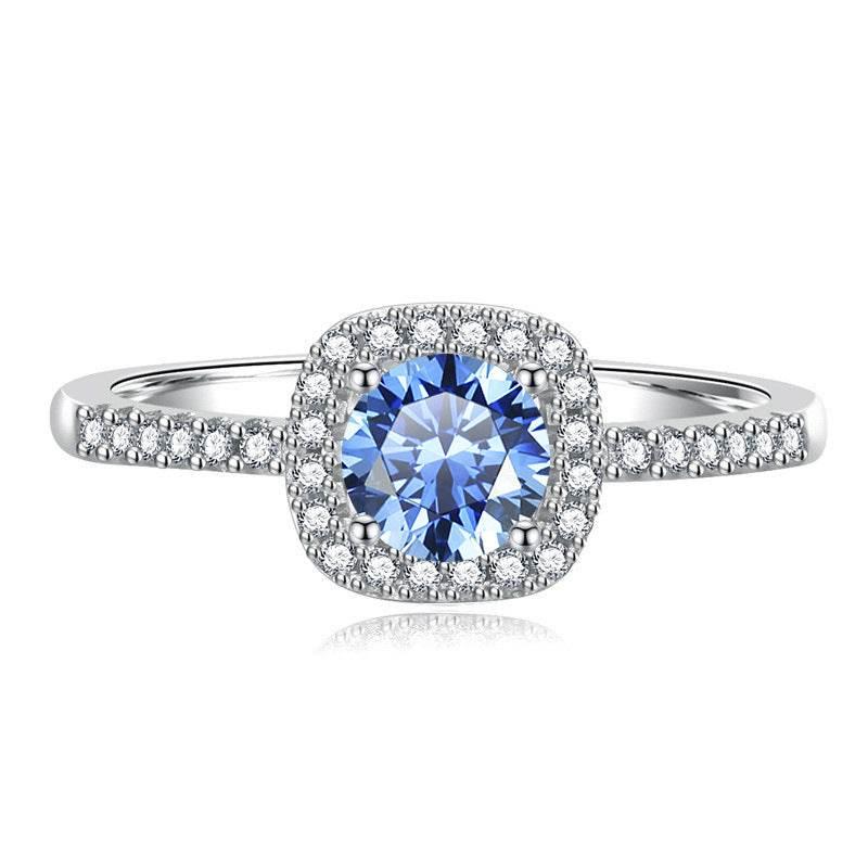 Madison sterling silver halo ring with a Klein Blue moissanite center stone and pavé-set band on a white background.