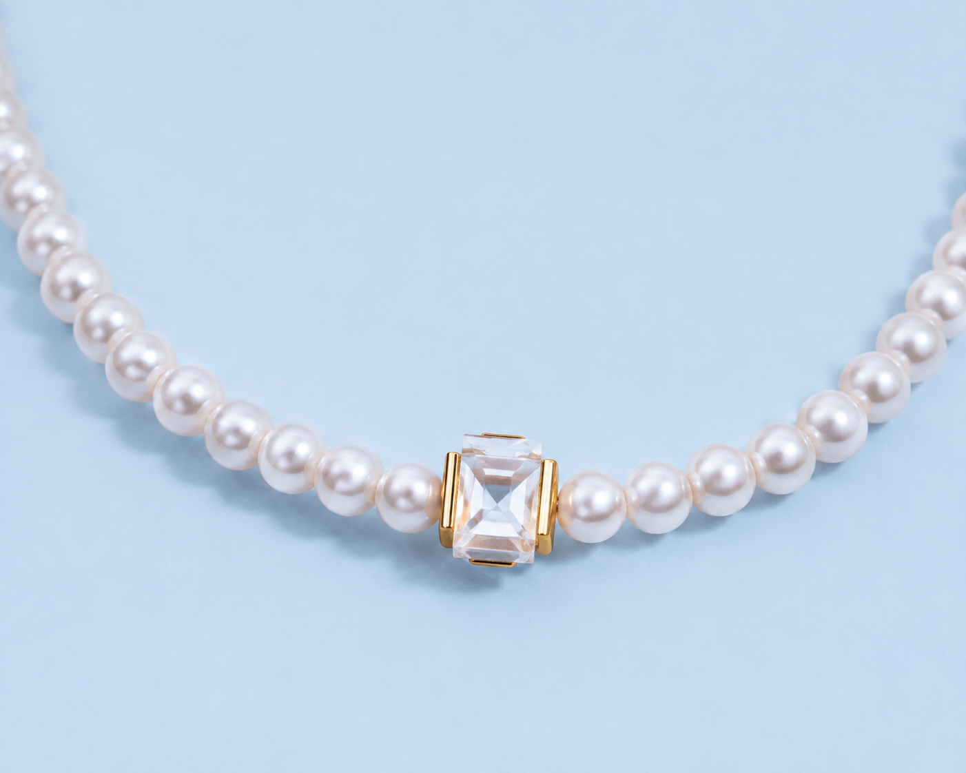 Close-up of the Marissa faux pearl necklace with a clear faceted square crystal in a gold-tone setting.