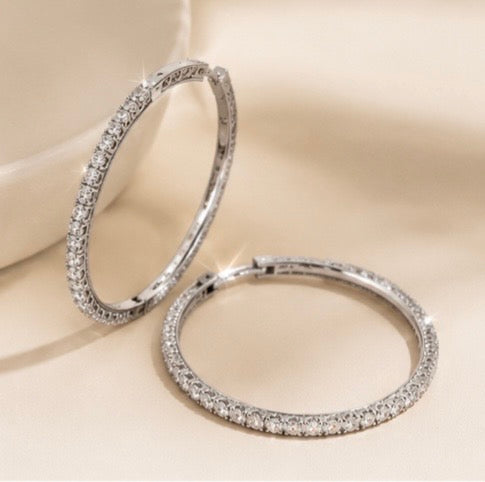 Monroe silver pavé hoop earrings with clear stones displayed on a beige background.