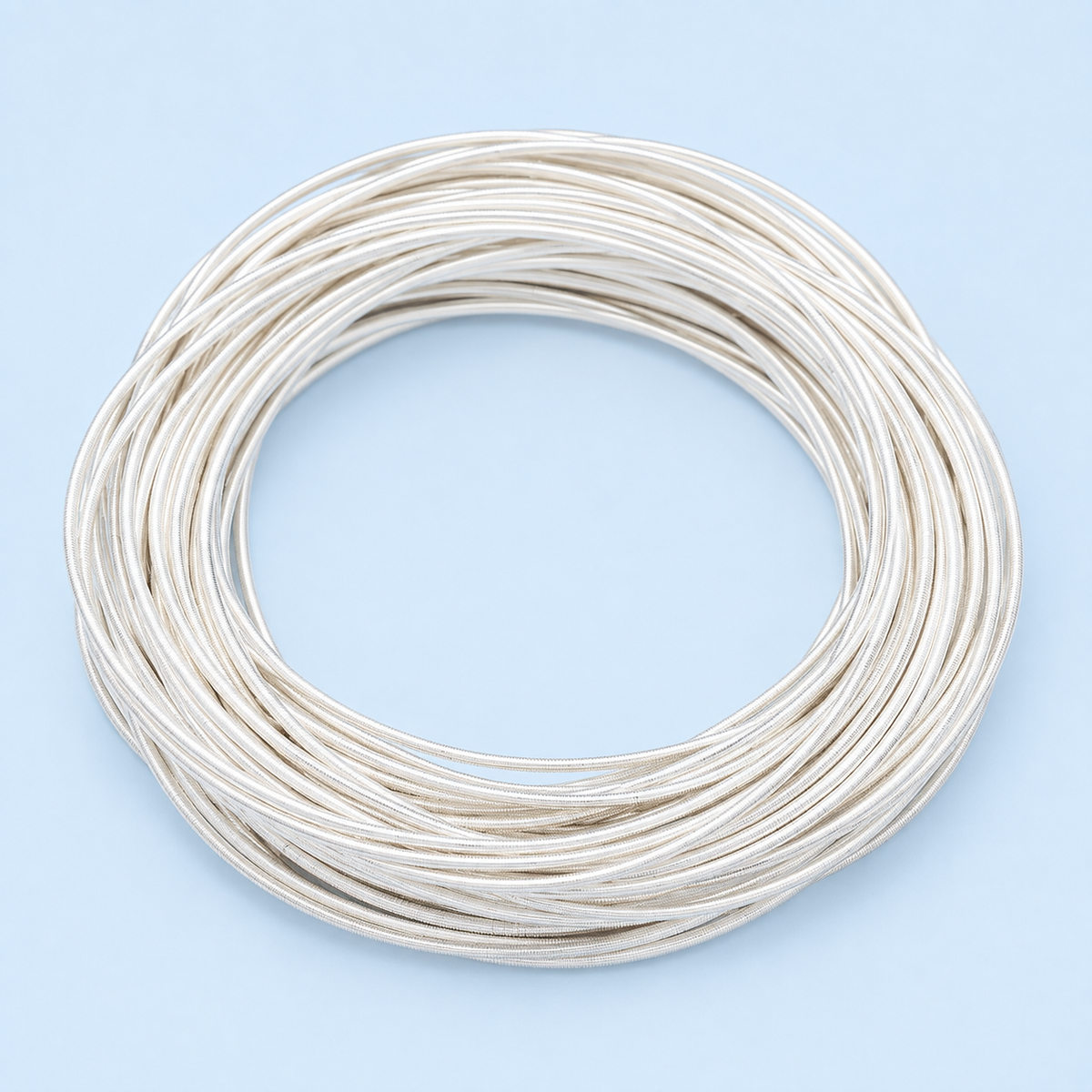 Neve silver-plated stacking bracelets arranged in overlapping circles on a pale blue background.