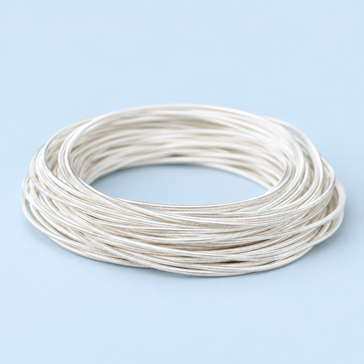 Angled close-up of Neve silver-plated stacking bracelets showing their fine coiled spring texture.