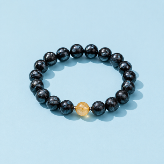 Onyx Arfvedsonite Gemstone Bracelet featuring dark blue-black beads and golden healer quartz on an RA blue background, The Riann Ashlyn Collection.