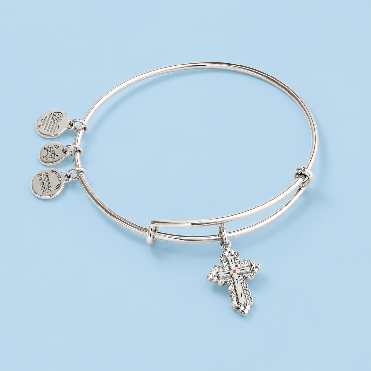     Paisley silver floral cross charm bangle bracelet on a pale blue background.