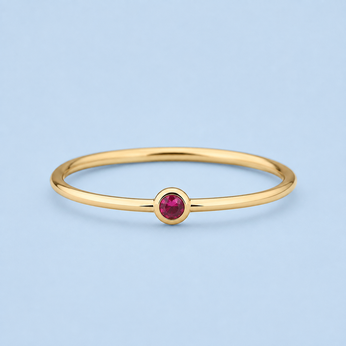     Riann Tiny Ruby Birthstone Ring in yellow gold on an RA blue background