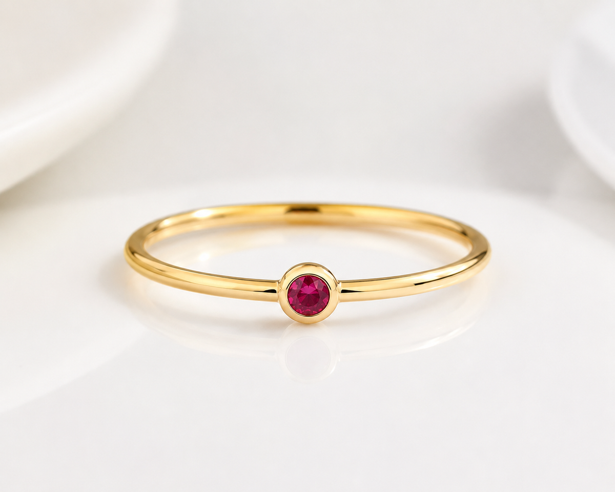     Close-up of Riann Tiny Ruby Birthstone Ring in yellow gold on a clean white background