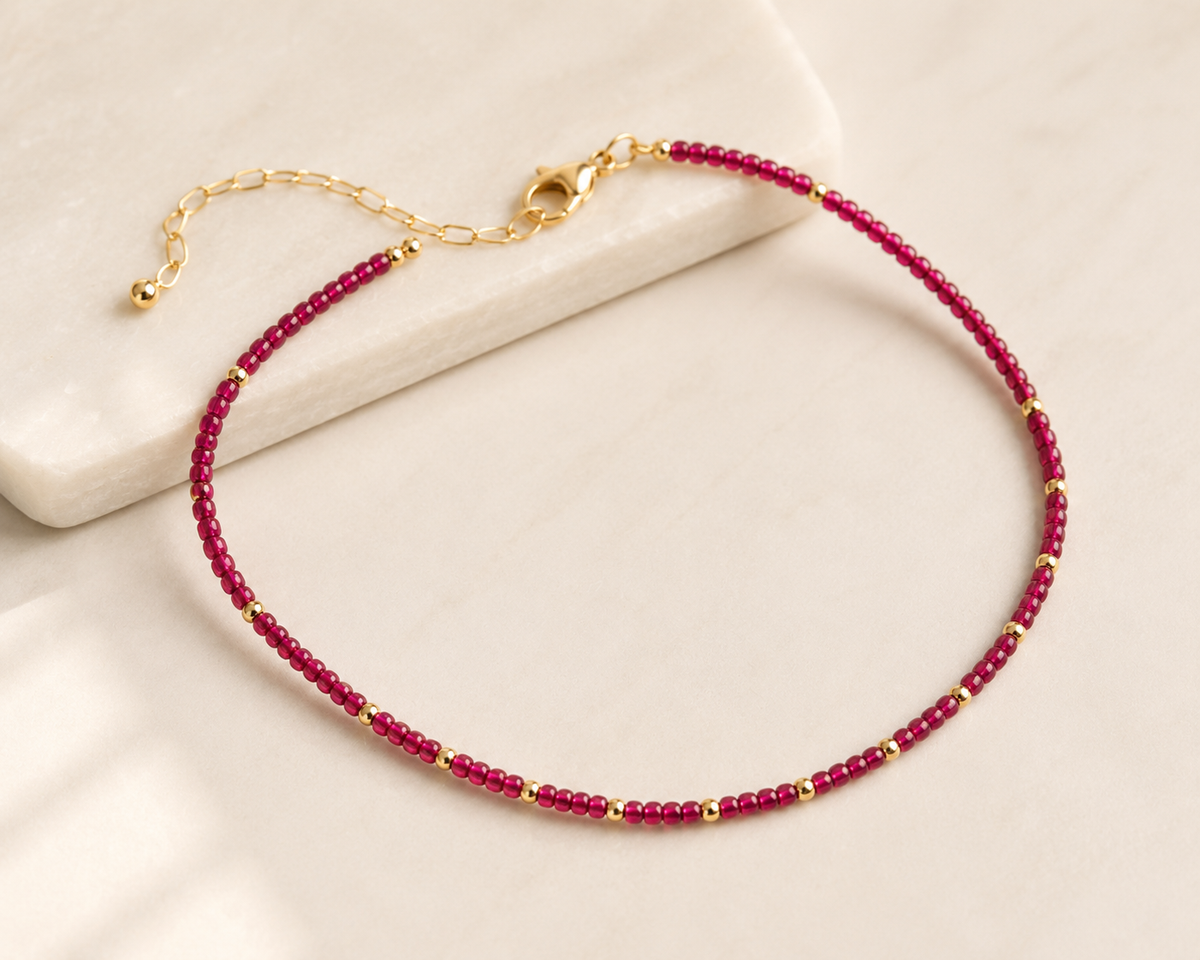 Rory Ruby Necklace with ruby-toned beads, gold-tone accents, lobster clasp, and extender chain.