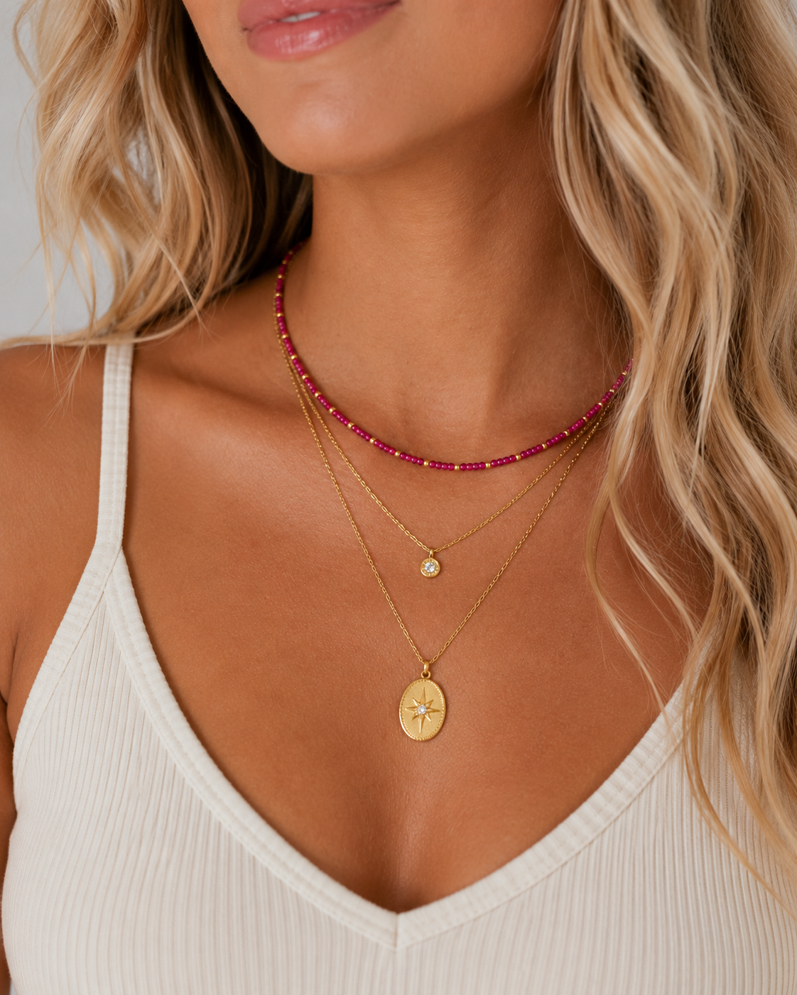 Rory Ruby Necklace layered with two gold pendant necklaces on a model.