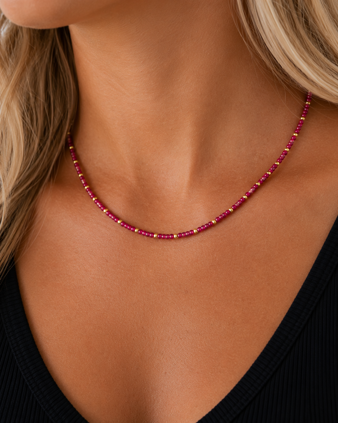 Close-up of a model wearing the Rory Ruby Necklace with ruby-toned beads and 18K gold-plated details.
