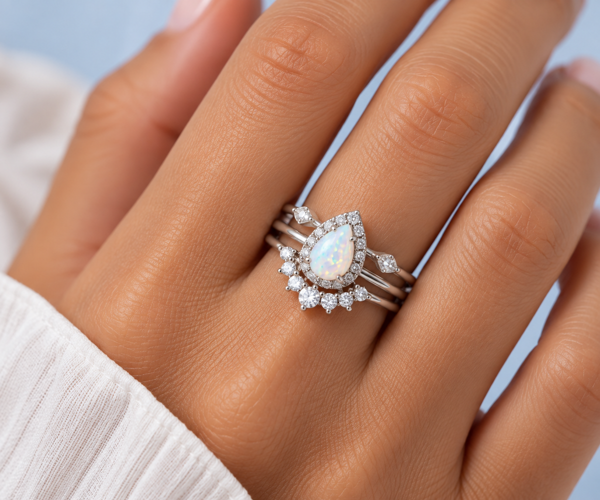 Close-up of Sutton silver pear opal ring set worn on hand