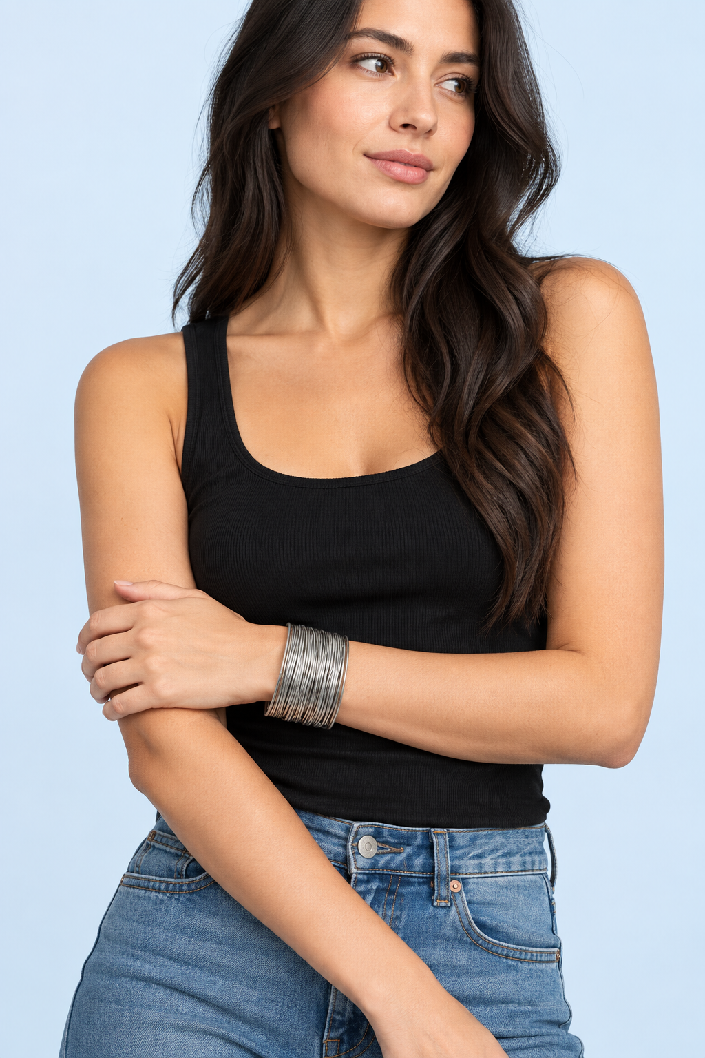 Model wearing a stack of Zadie silver spring bracelets with a black top against a pale blue background
